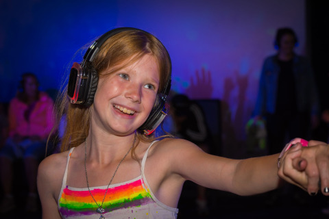 Smiling girl with headphones dances at a silent disco event at Camping Samoza – Glamping Lodges Veluwe.