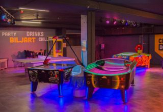 Sala giochi interna al Camping Samoza – Glamping Lodges Veluwe con tavoli da air hockey e giochi arcade.