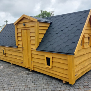 A fairytale-style wooden glamping cabin at Camping Rissbach, Rhineland-Palatinate, with a black roof.