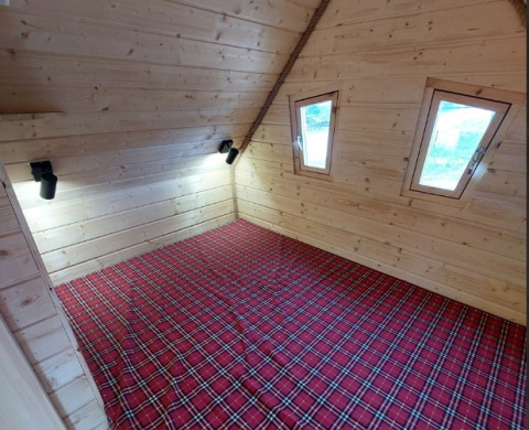 Innenraum des Sprookjeshuis bei Camping Rissbach, Holzwände, rote Karodecke, kleine Dachfenster.