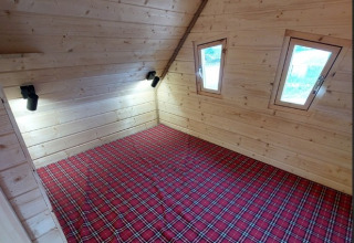 Interieur van het Sprookjeshuis bij Camping Rissbach, houten wanden, rood geruit tapijt en dakramen.