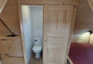 Indvendig udsigt af glamping hus med toilet, vask og seng hos Camping Rissbach - Sprookjeshuis Rijnland-Palts.
