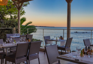 Udendørs restaurantudsigt ved solnedgang ved havet på Camping Bagheera – Eco lodges Corsica.