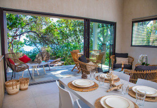 Modern glamping accommodation with dining and lounge area overlooking the forest at Camping Bagheera, Corsica.