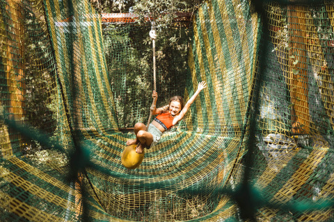 Barn leger på netbaner i trætoppe hos Camping Bagheera – Eco lodges Corsica, omgivet af natur.
