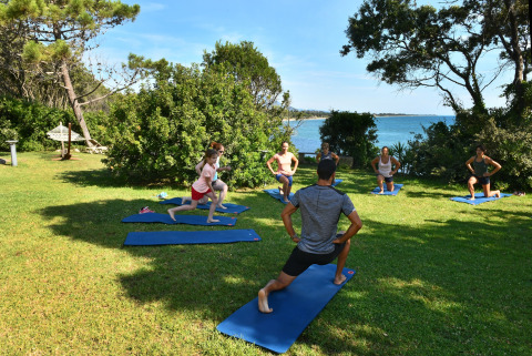 Outdoor yoga class at Camping Bagheera – Eco lodges Corsica, surrounded by greenery with sea views.
