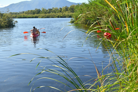People kayaking on a peaceful lake surrounded by nature at Camping Bagheera – Eco lodges Corsica.