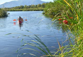 Mensen kajakken op een rustige plas bij Camping Bagheera – Eco lodges Corsica, omgeven door natuur.