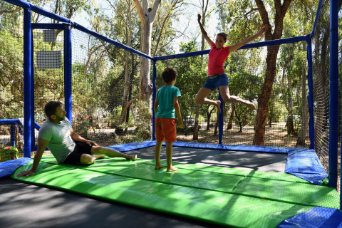 Familia divirtiéndose en una cama elástica durante su estancia en Camping Bagheera – Eco lodges Córcega.