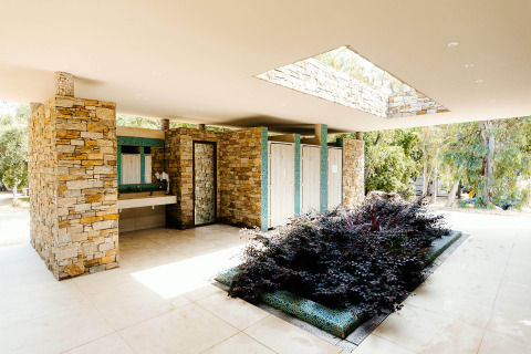 Modernos aseos de piedra con plantas en Camping Bagheera – Eco lodges Corsica, integrados en la naturaleza.