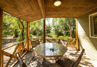 Veranda in legno con tavolo e sedie immersa nella natura al Camping Bagheera – Eco lodges Corsica, ideale per glamping.