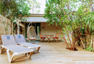 Outdoor deck at Camping Bagheera – Eco lodges Corsica featuring loungers, a hanging chair and furniture.