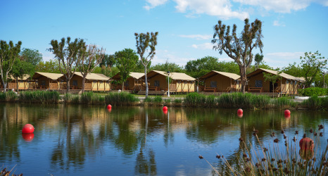 Hébergement glamping avec tentes au bord d’un lac et arbres au Camping Nautic Almata – Glamping Costa Brava.