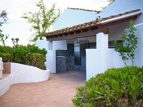 Zona de cocina exterior con paredes blancas y vegetación en Camping Nautic Almata – Glamping Costa Brava.