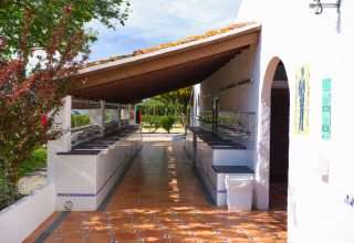 Buitengebied met gezamenlijke wasbakken op Camping Nautic Almata – Glamping Costa Brava in de zon.