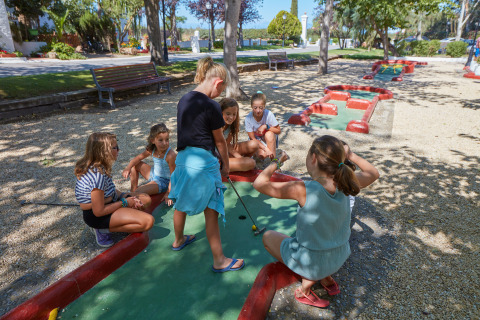 Kinder spielen Minigolf im Freien bei Camping Nautic Almata – Glamping Costa Brava mit Bäumen im Hintergrund.