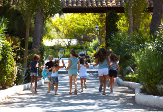 Children running with tennis rackets at Camping Nautic Almata – Glamping Costa Brava, surrounded by greenery.