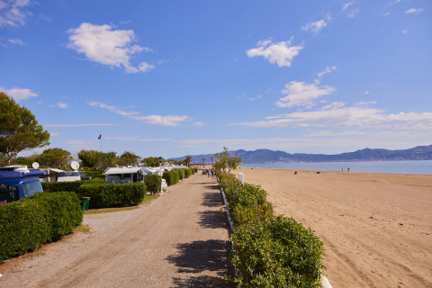 Vista de Camping Nautic Almata – Glamping Costa Brava con caravanas junto a la playa y cielo despejado.