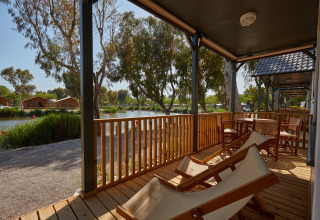 Holzveranda mit Liegestühlen und Blick auf den See im Camping Nautic Almata – Glamping Costa Brava.