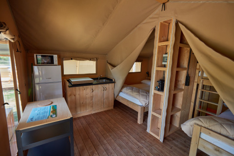 Vista interna dell’alloggio glamping presso Camping Nautic Almata, Glamping Costa Brava, con cucina e letti.