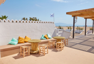 Area salotto esterna al Camping Nautic Almata – Glamping Costa Brava con vista spiaggia e cuscini colorati.