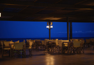 Area pranzo all'aperto al Camping Nautic Almata – Glamping Costa Brava sul mare al crepuscolo.