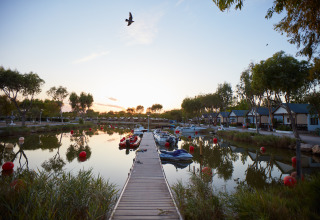 Camping Nautic Almata – Glamping Costa Brava met steiger, boten, huisjes en rustige sfeer aan het water bij zonsondergang.