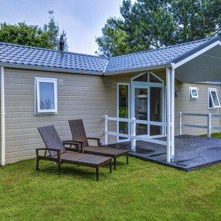 Moderne glampinghytte med overdækket terrasse og liggestole på Camping og feriepark Wulfener Hals ved Østersøen.