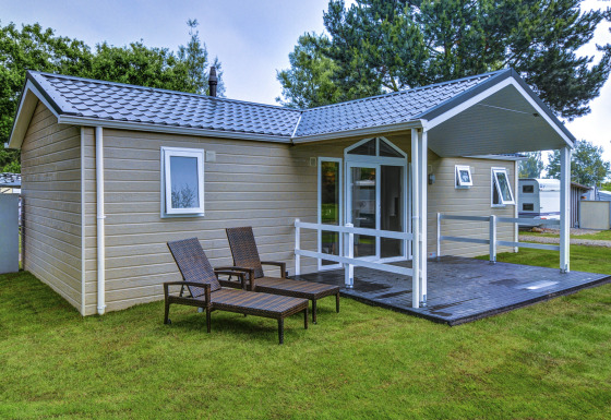 Moderne glamping stacaravan met overdekt terras en ligstoelen op camping Wulfener Hals aan de Oostzee.