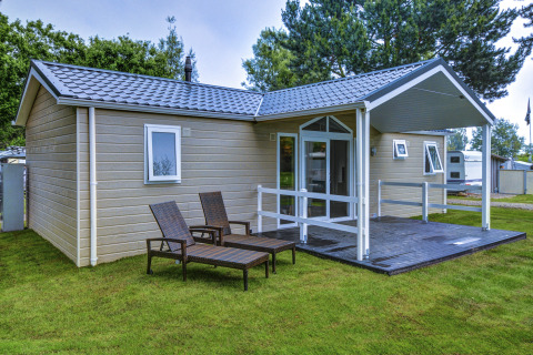 Moderne glamping stacaravan met overdekt terras en ligstoelen op camping Wulfener Hals aan de Oostzee.