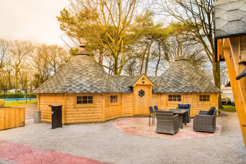 Glamping accommodation Finnish Kota at Camping Beringerzand Limburg, exterior view with outdoor furniture.