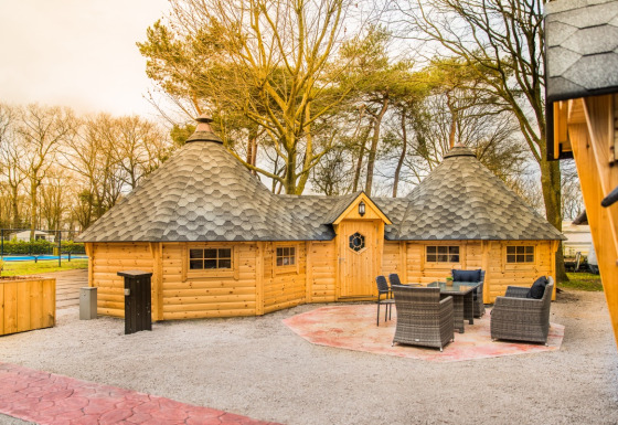 Glamping-Unterkunft Finse Kota im Camping Beringerzand Limburg, außen mit Sitzgruppe und Bäumen im Hintergrund.