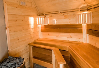 Binnenaanzicht van een sauna met houten banken en saunastenen bij Camping Beringerzand - Finse Kota's Limburg.