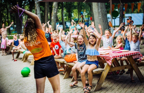 Bambini partecipano a giochi all'aperto a Camping Beringerzand - Finse Kota's Limburg tra gli alberi.
