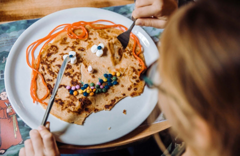 Kindje eet pannenkoek met gezichtje van snoep bij Camping Beringerzand - Finse Kota's Limburg.