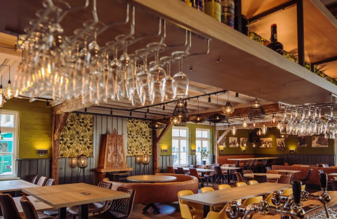 Indbydende restaurant med træmøbler og hængende vinglas på Camping Beringerzand - Finse Kota's Limburg.