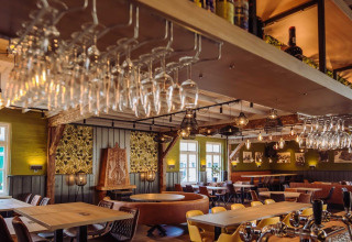 Indbydende restaurant med træmøbler og hængende vinglas på Camping Beringerzand - Finse Kota's Limburg.