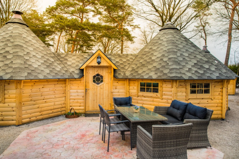 Espace détente extérieur devant une cabane en bois aux toits coniques au Camping Beringerzand, Limbourg.