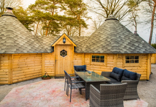 Buiten zitgedeelte voor een unieke houten hut met kegelvormige daken op Camping Beringerzand in Limburg.