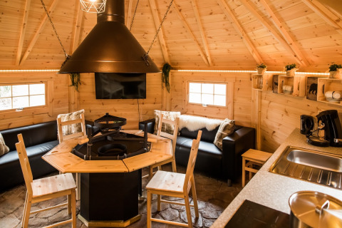 Indvendigt billede af en Finse Kota i Camping Beringerzand Limburg med grill, sofaer og køkken.