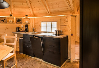 Cozy wooden interior of a Finse Kota at Camping Beringerzand featuring a compact kitchen and dining area.