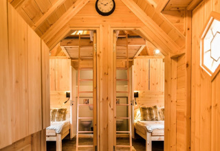 Vista interna della sistemazione glamping Camping Beringerzand - Finse Kota's Limburg con arredo in legno e letti.