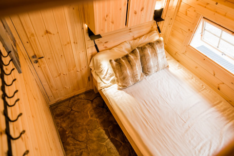 Lyst, hyggeligt interiør i træ med dobbeltseng og vindue på Camping Beringerzand - Finse Kota's Limburg.