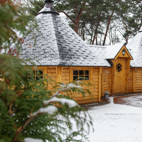 Snow-dusted Finse Kota glamping cabin at Camping Beringerzand Limburg, surrounded by forest in wintertime.