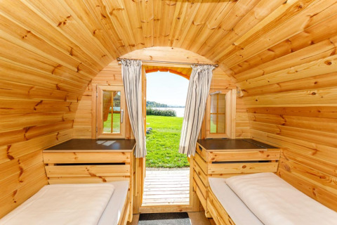 Interior of a cozy wooden glamping pod at Camping Pilsensee - Wijnvaten Beieren with a scenic lake view outside.