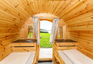 Knusse houten kampeerhut bij Camping Pilsensee - Wijnvaten Beieren met uitzicht op grasveld en meer buiten.