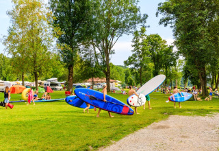 Mensen kamperen en dragen paddleboards bij Camping Pilsensee - Wijnvaten Beieren op een zonnige dag.