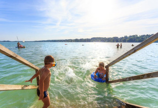 Kinderen spelen bij de steiger aan het meer op Camping Pilsensee - Wijnvaten Beieren op een zonnige dag.