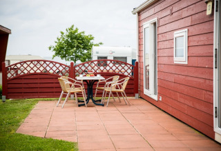 Buiten terras met vier stoelen en tafel bij een rood vakantiehuisje op Vakantiepark Ostseecamping Zierow.