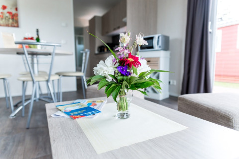 Helles Interieur einer Glamping-Unterkunft im Vakantiepark Ostseecamping Zierow mit Blumenstrauß am Tisch.